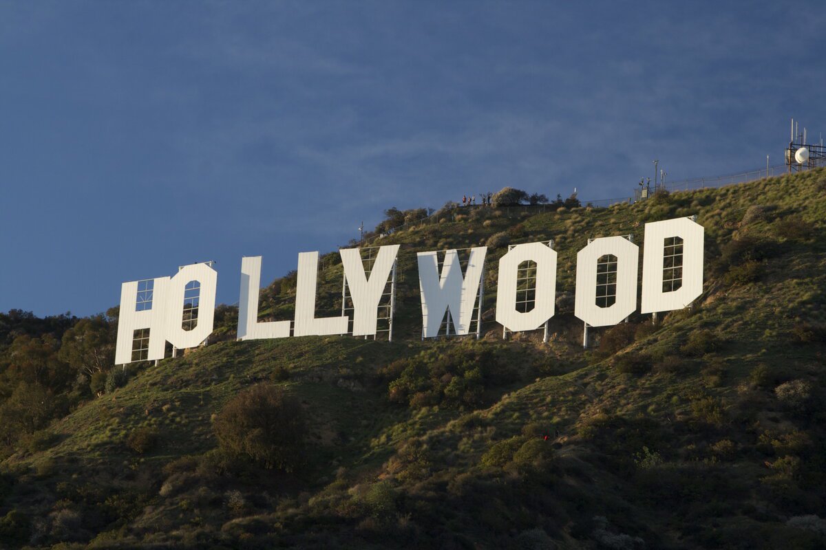 The white Hollywood sign on a green hillside under a deep blue evening sky