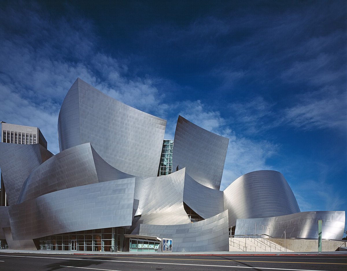 The curved stainless steel exterior of Walt Disney Concert Hall on Grand Avenue under a deep blue sky