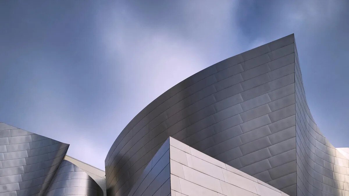 Curved stainless steel panels of Walt Disney Concert Hall against a blue sky