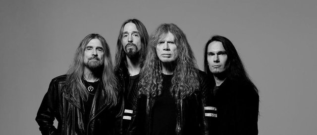 Black and white portrait of the four members of Megadeth in leather jackets against a gray backdrop