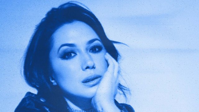 Michelle Branch resting her chin on her hand in a blue-tinted, grainy portrait used for her Everywhere And Back Again Tour