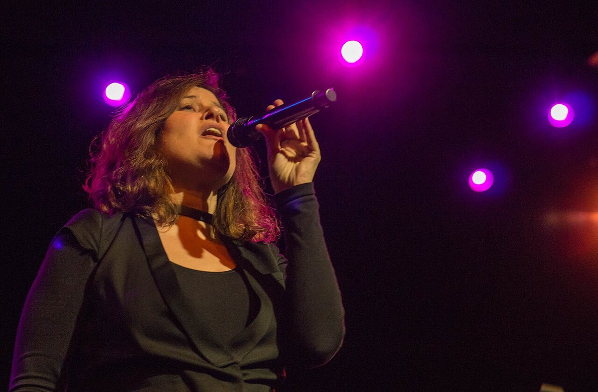 Paula Cole performing live on stage with a microphone