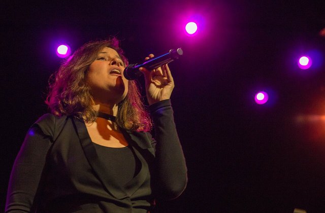 Paula Cole performing live on stage with a microphone