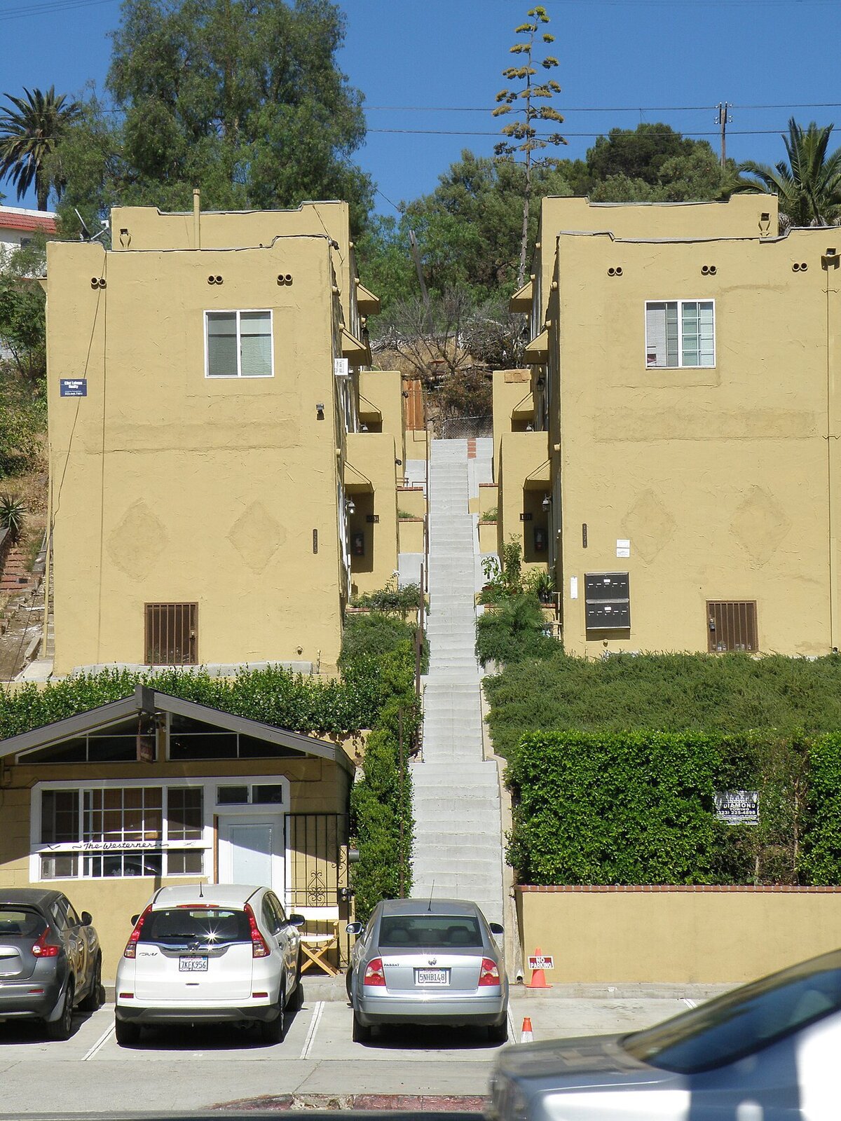 Concrete staircase climbing between two stucco apartment buildings on a hillside street in Los Angeles