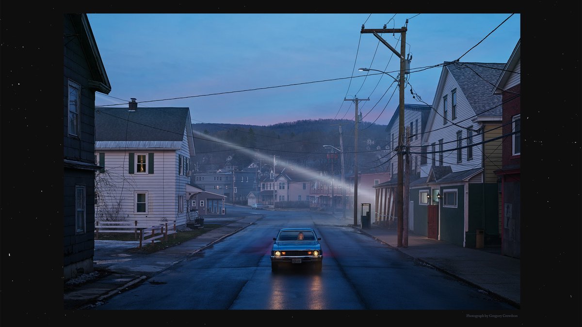 Tour artwork for The Lost Tour showing a lone car with its headlights on, driving down a misty small-town street at dusk