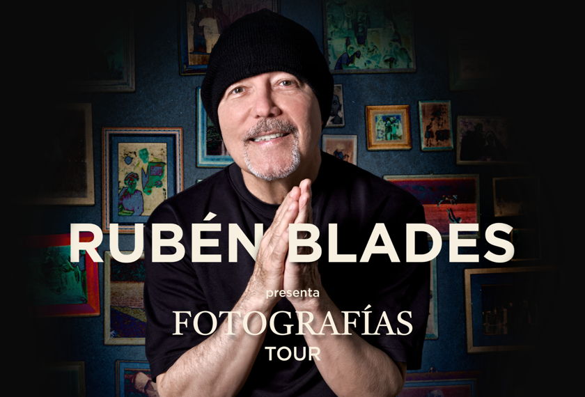Rubén Blades in a black beanie with his palms pressed together, in front of a wall of framed pictures, on the Fotografías Tour poster