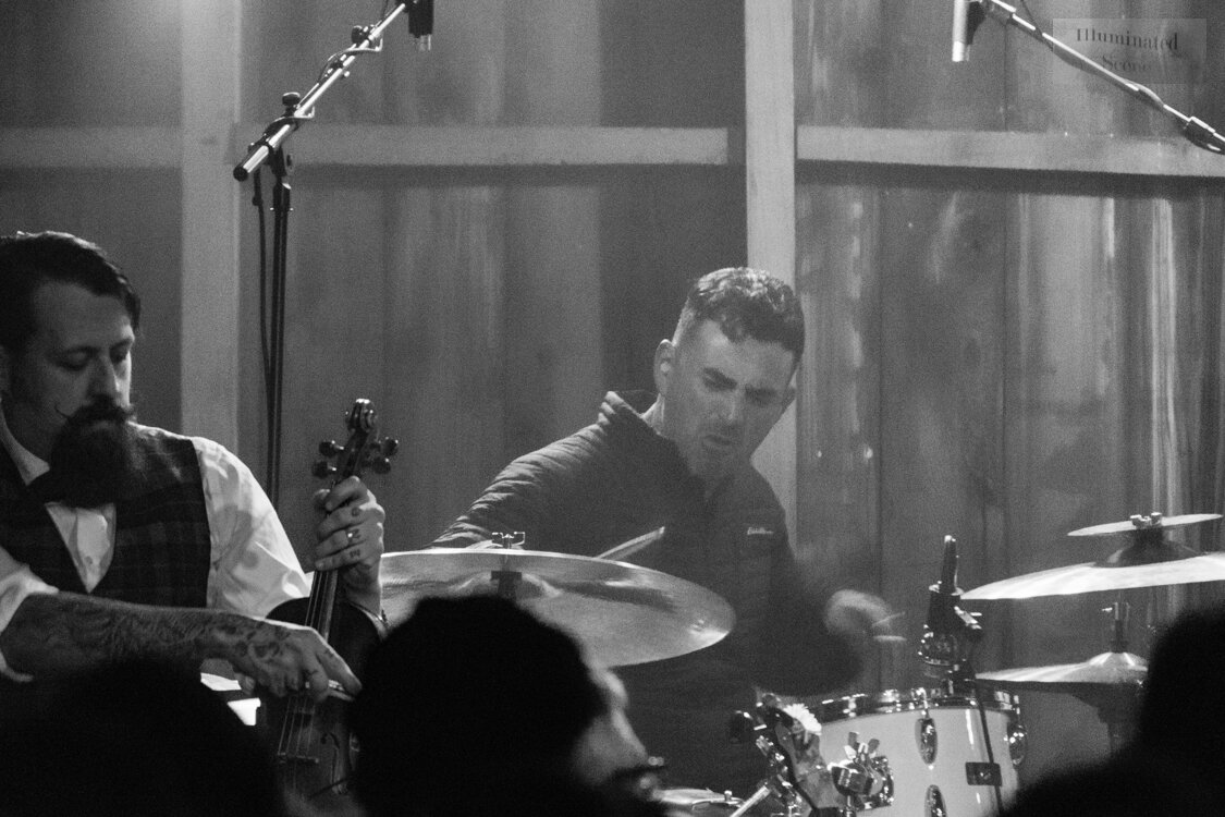 Black-and-white photo of a fiddle player and a drummer from Squirrel Nut Zippers on stage