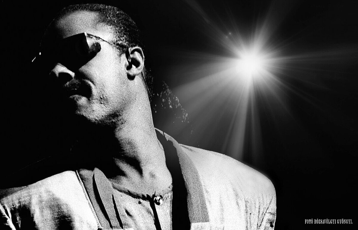 Black-and-white portrait of Stevie Wonder in sunglasses, lit by a bright stage light