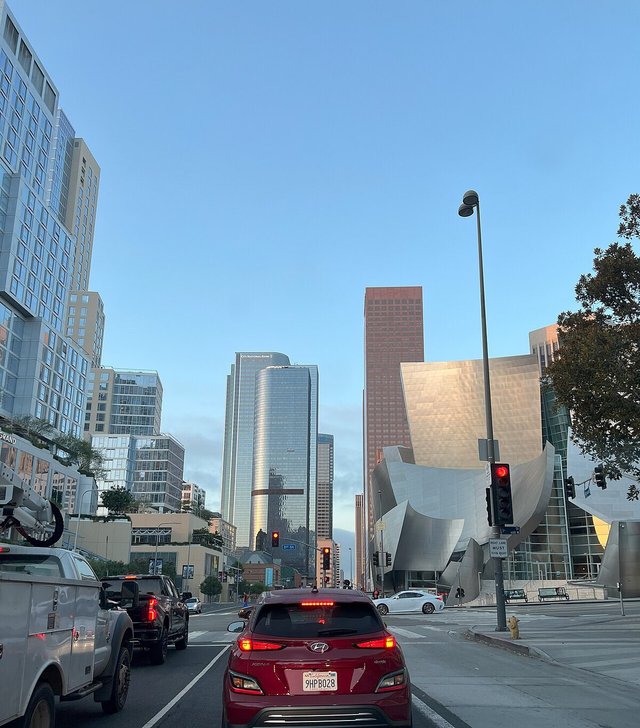Downtown Los Angeles street at dusk with glass towers and the Walt Disney Concert Hall on Grand Avenue