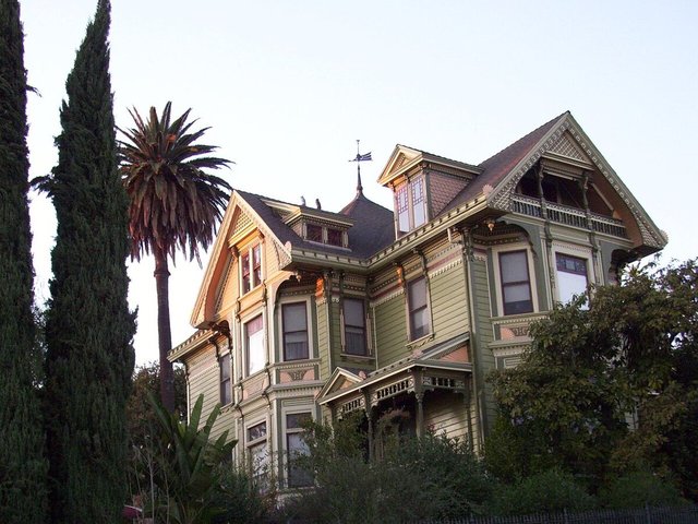 Green Victorian house with a tall palm tree and cypress trees in Angelino Heights, near Echo Park