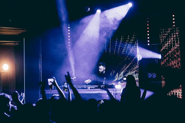 A DJ performing on stage in front of a crowd at a drum and bass night