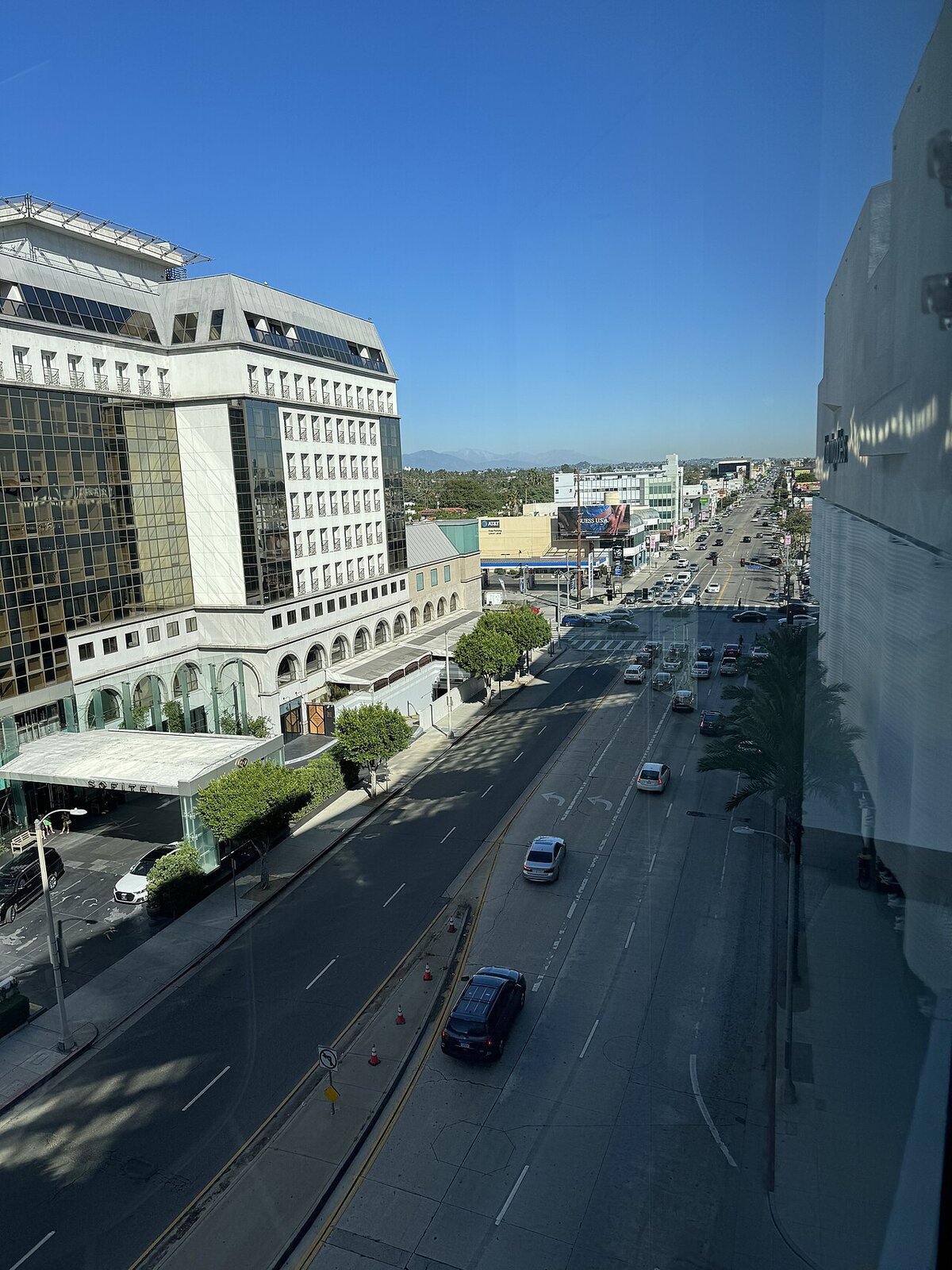 Beverly Boulevard seen from above on a clear day, with a hotel on the left and traffic heading toward the Hollywood hills