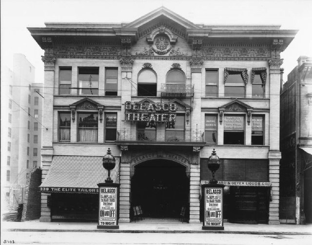 Black and white historic photo of the Belasco Theater facade in Los Angeles with posters out front