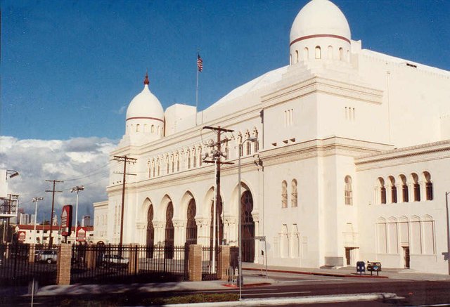 White domed Shrine Auditorium building on Jefferson Boulevard under a blue sky, next door to Shrine Expo Hall