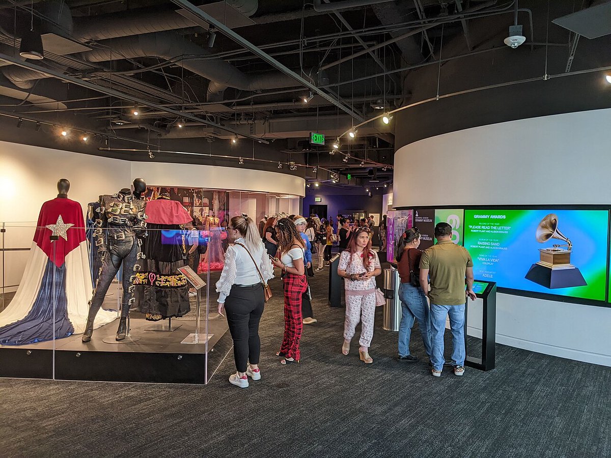 Visitors browsing costume displays and a Grammy Awards screen inside the Grammy Museum in Los Angeles
