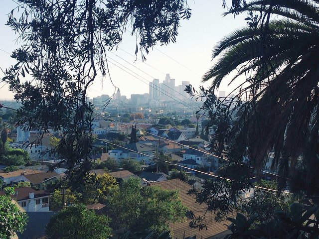 Hillside view over the rooftops of Lincoln Heights toward the Downtown Los Angeles skyline, the neighborhood around The Airliner