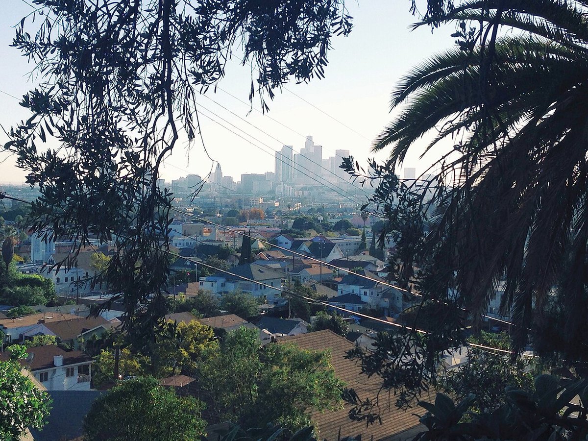 Hillside view over the rooftops of Lincoln Heights toward the Downtown Los Angeles skyline, the neighborhood around The Airliner