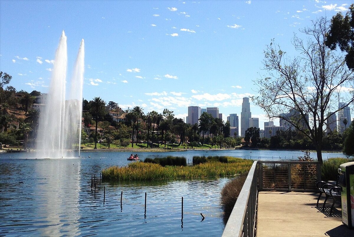 Fountain spraying on Echo Park Lake with a paddle boat and the downtown Los Angeles skyline behind it