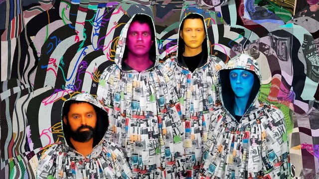 The four members of Animal Collective in matching hooded robes printed with collage photos, their faces painted pink, yellow, blue and orange, standing in front of a swirling black, white and neon patterned backdrop
