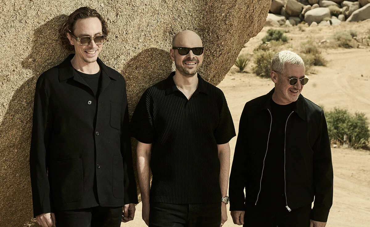 The three members of Above & Beyond standing in front of a desert rock formation