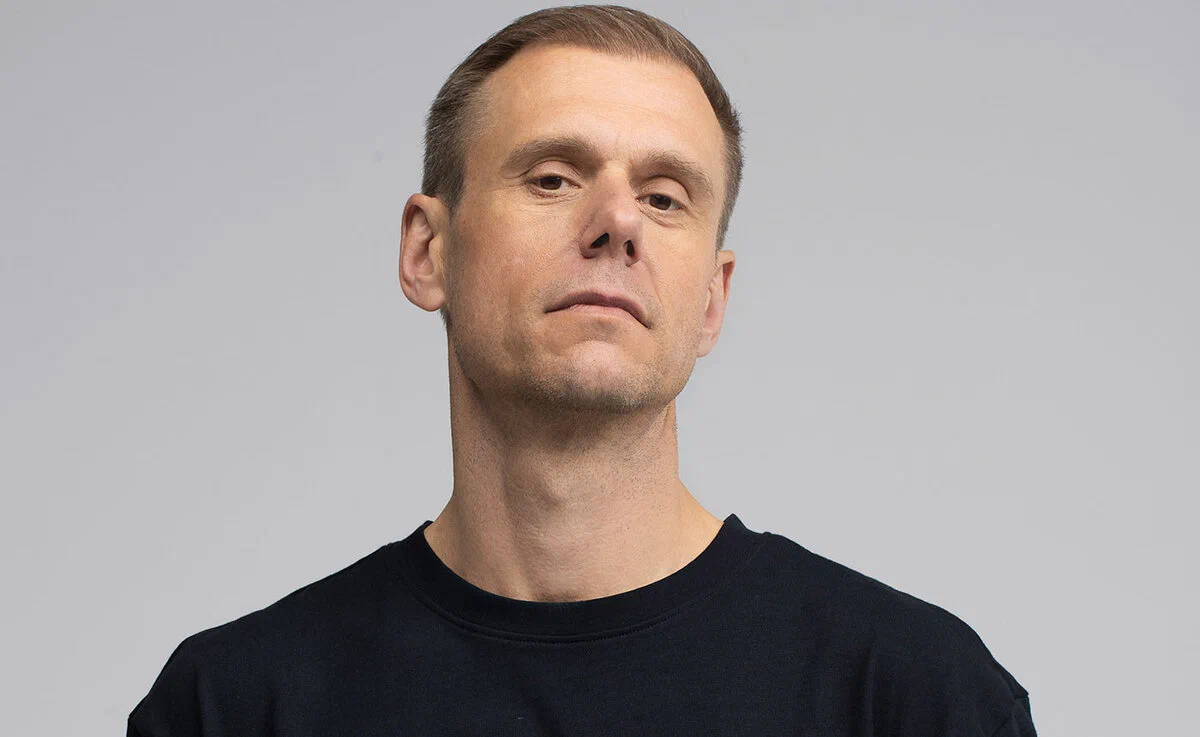 Armin van Buuren in a plain black t-shirt against a grey backdrop in a promo portrait