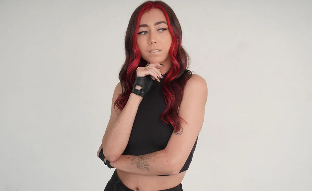Clawz posing with one hand raised in a studio promo portrait