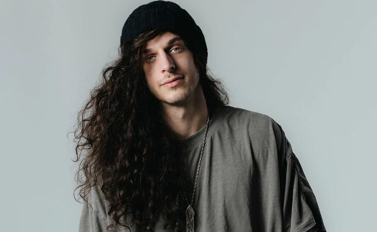 Subtronics with long curly hair under a beanie in a promo portrait