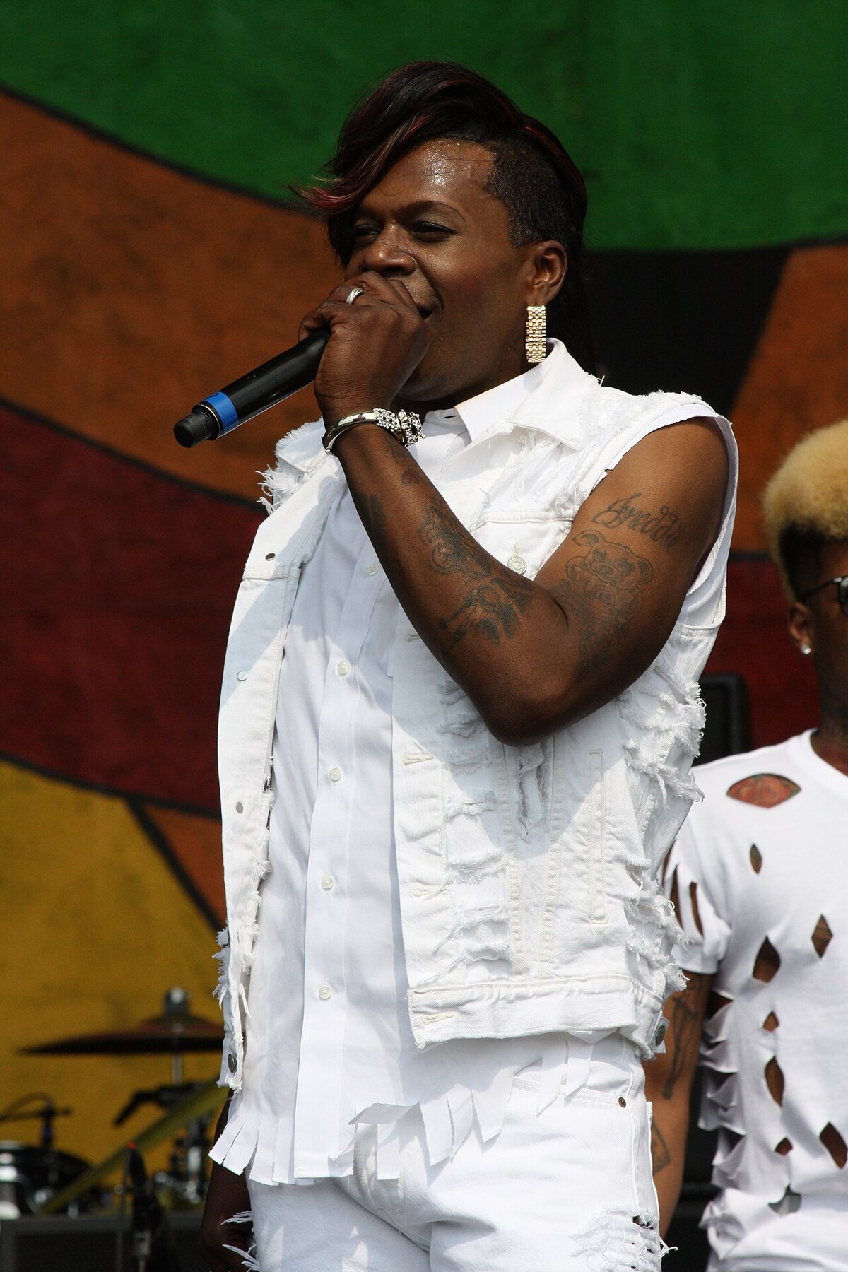 Big Freedia on stage in a white denim vest, holding a microphone to her mouth