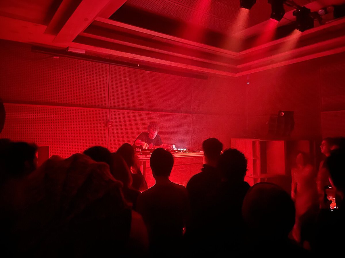 Photay performing a live electronic set behind a table of synths and mixers