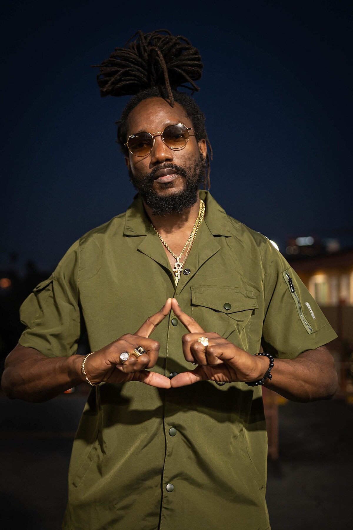 Portrait of Kabaka Pyramid at night, making a triangle shape with his hands
