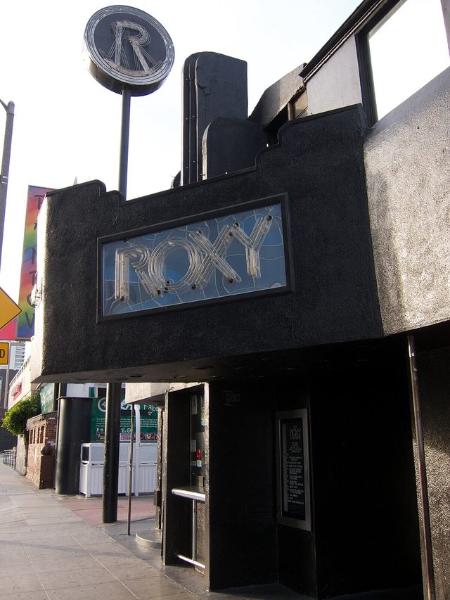 The Roxy's black stucco front on Sunset Boulevard with its lit ROXY sign above the entrance