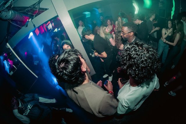 A crowd of people dancing together at a New Year's Eve party with colorful lighting