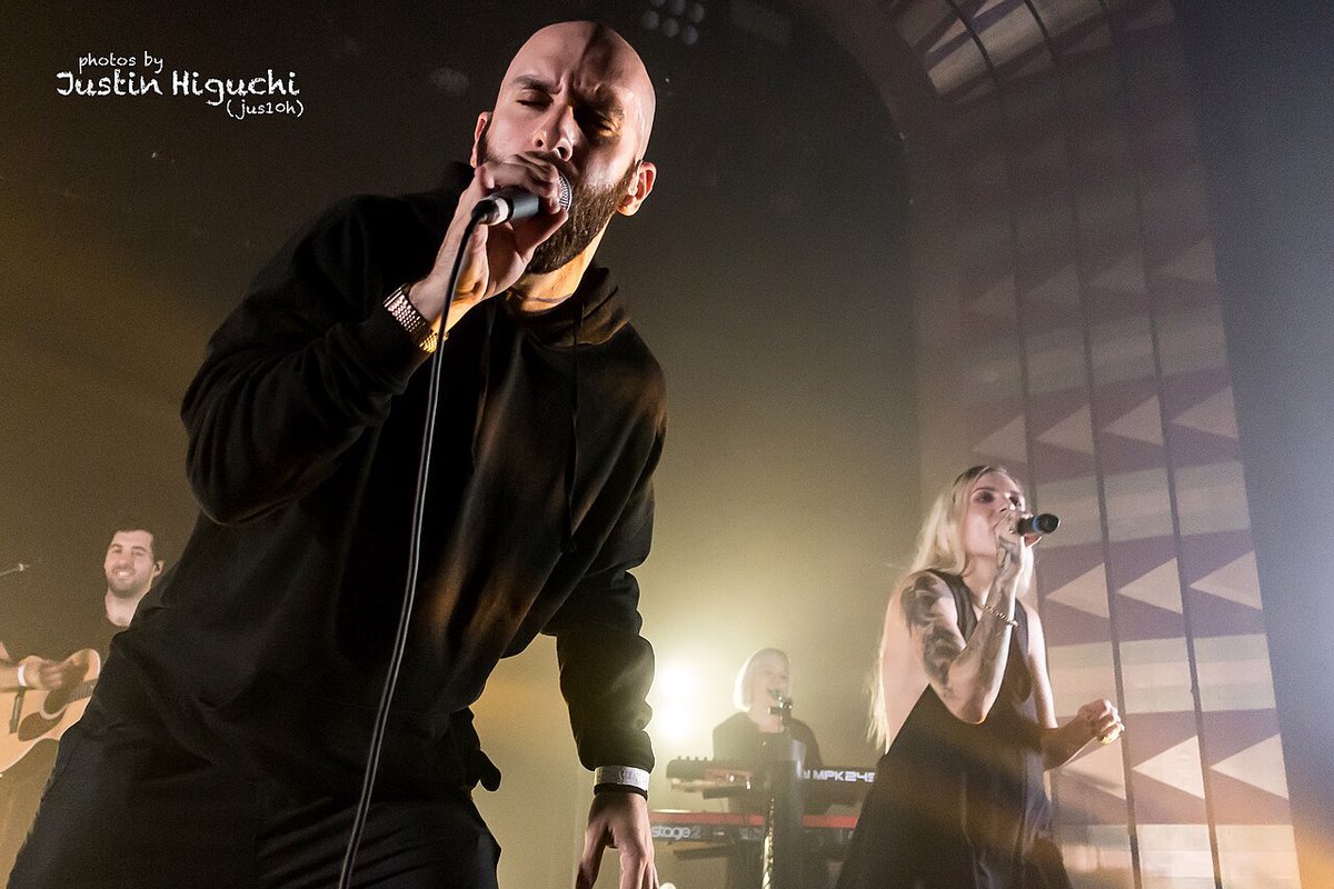 Two musicians performing on a stage with soft stage lighting and a smoky backdrop