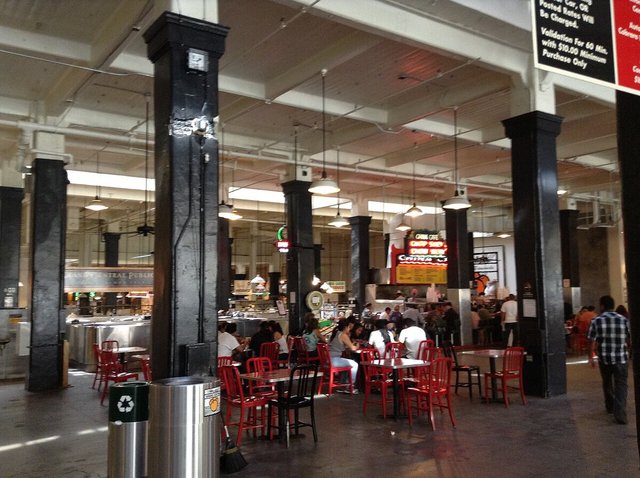 Diners at red tables inside the Grand Central Market food hall in downtown Los Angeles