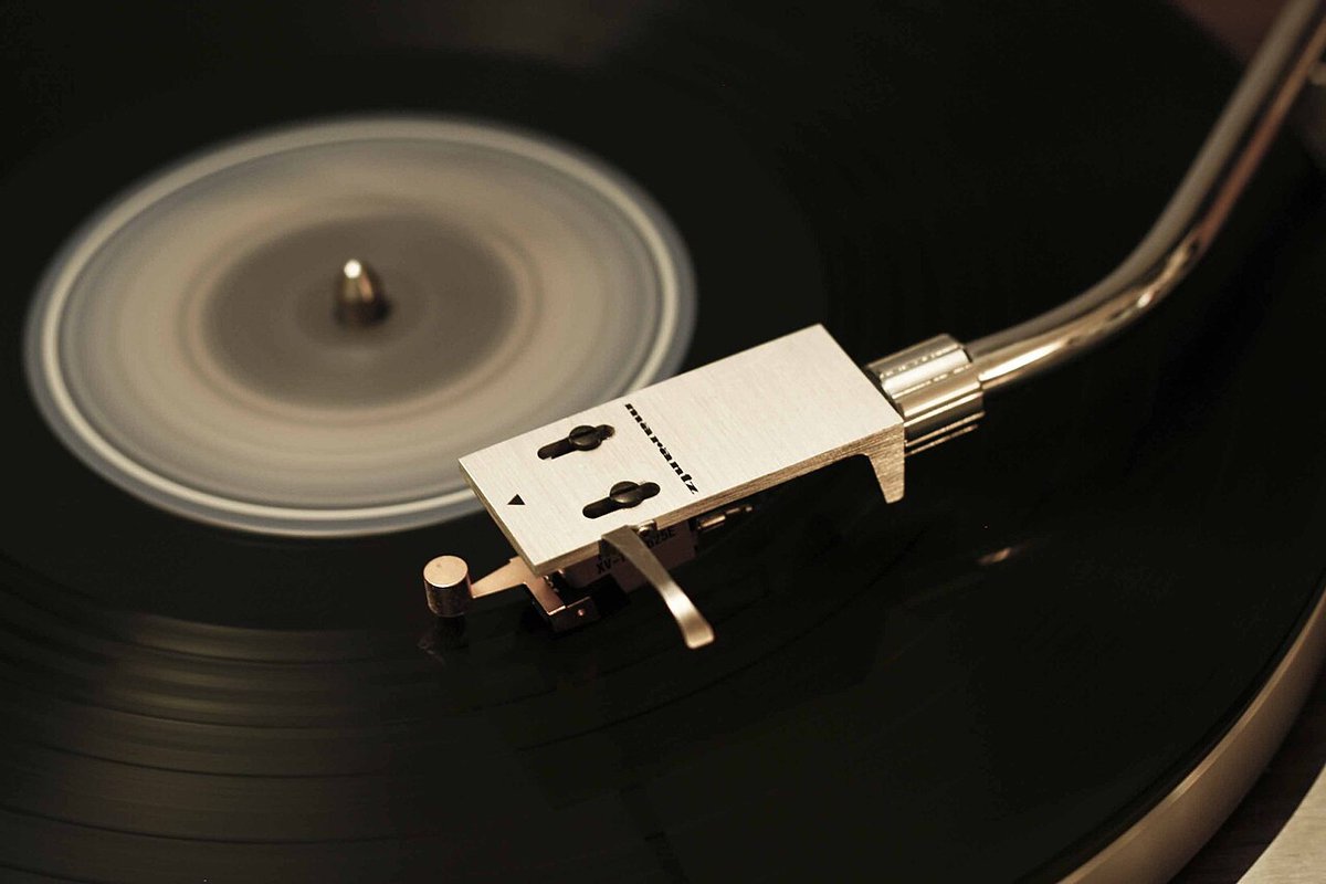 Close-up of a turntable tonearm and headshell resting on a spinning black vinyl record