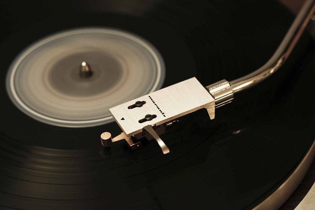 Close-up of a turntable tonearm and headshell resting on a spinning black vinyl record