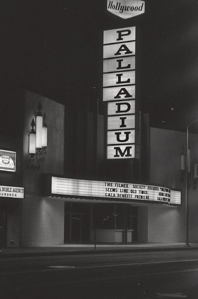 Black-and-white night photo of the vertical Palladium sign and lit marquee on Sunset Boulevard in Hollywood