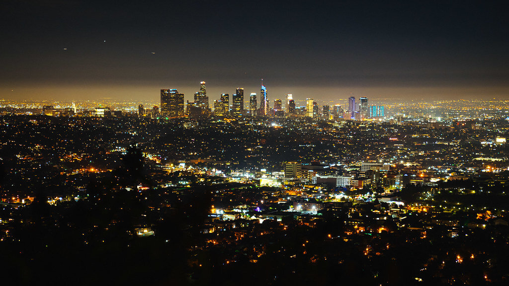 Downtown Los Angeles skyline glowing at night, seen from the hills across the city