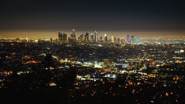Downtown Los Angeles skyline glowing at night, seen from the hills across the city