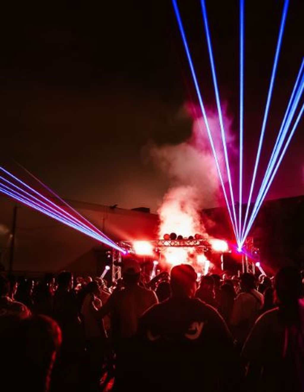 Crowd facing a smoky stage lit by blue and red lasers at night