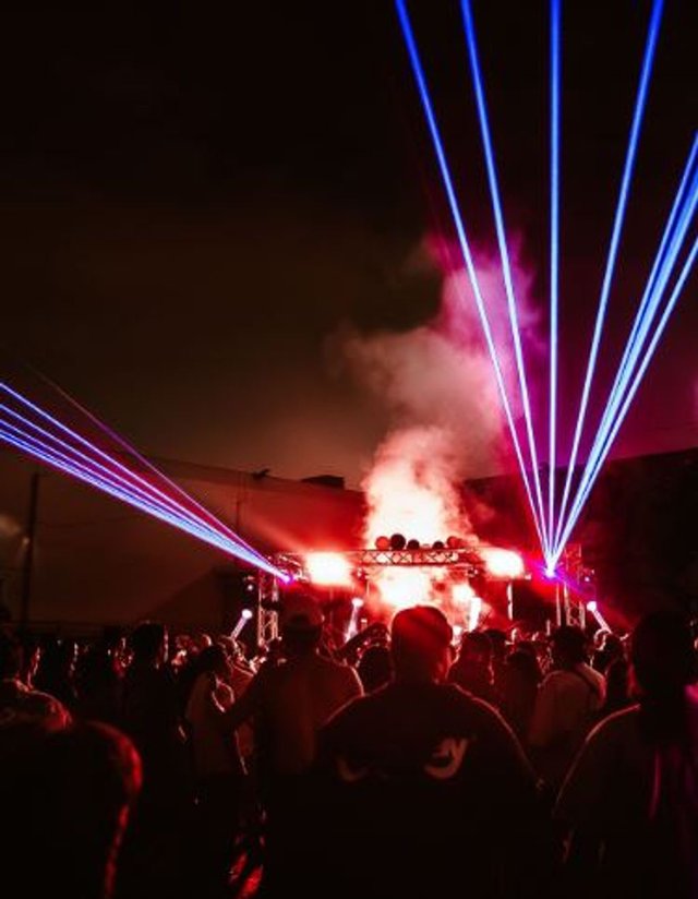 Crowd facing a smoky stage lit by blue and red lasers at night