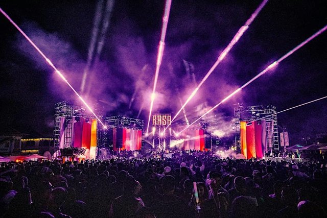 Pink laser beams fanning out over a packed crowd in front of a RASA-branded stage at night