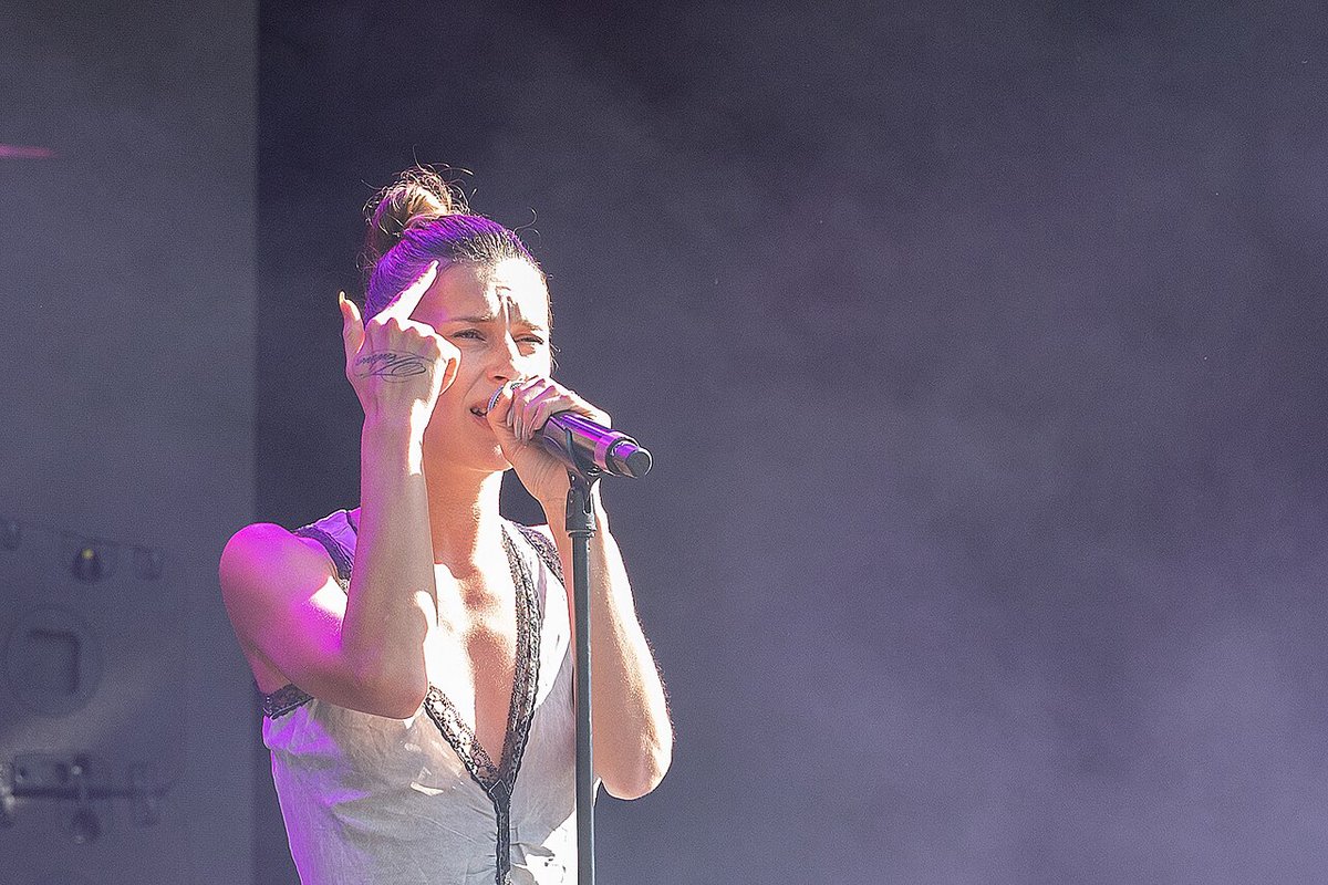 Qendresa singing into a microphone on an outdoor festival stage