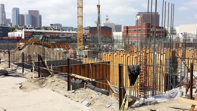 Downtown Los Angeles skyline rising behind a construction site and a graffiti-covered wall in the Arts District