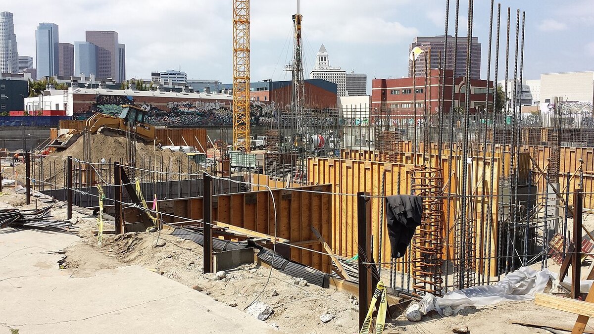Downtown Los Angeles skyline rising behind a construction site and a graffiti-covered wall in the Arts District
