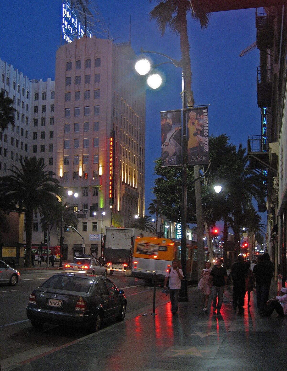 Hollywood Boulevard at dusk with palm trees, neon signs and pedestrians on the Walk of Fame