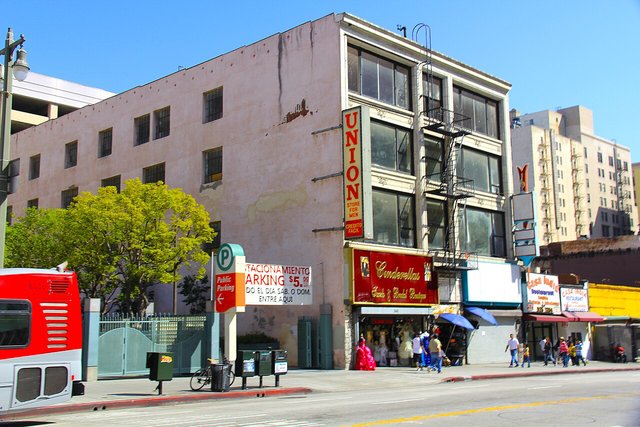 Storefronts and a pink building along South Broadway in Downtown Los Angeles on a sunny day
