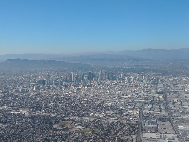 Aerial view of the Downtown Los Angeles skyline with mountains in the haze behind it