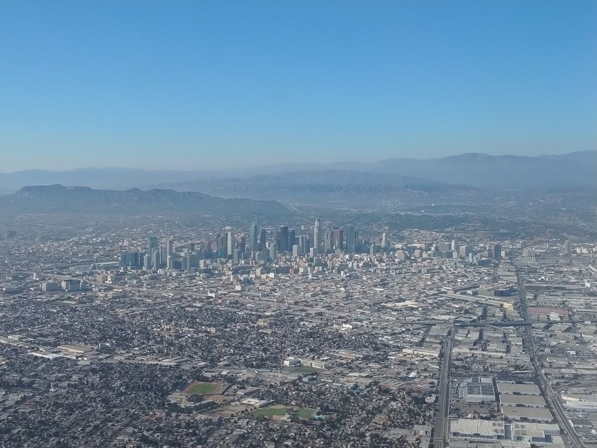 Aerial view of the Downtown Los Angeles skyline with mountains in the haze behind it