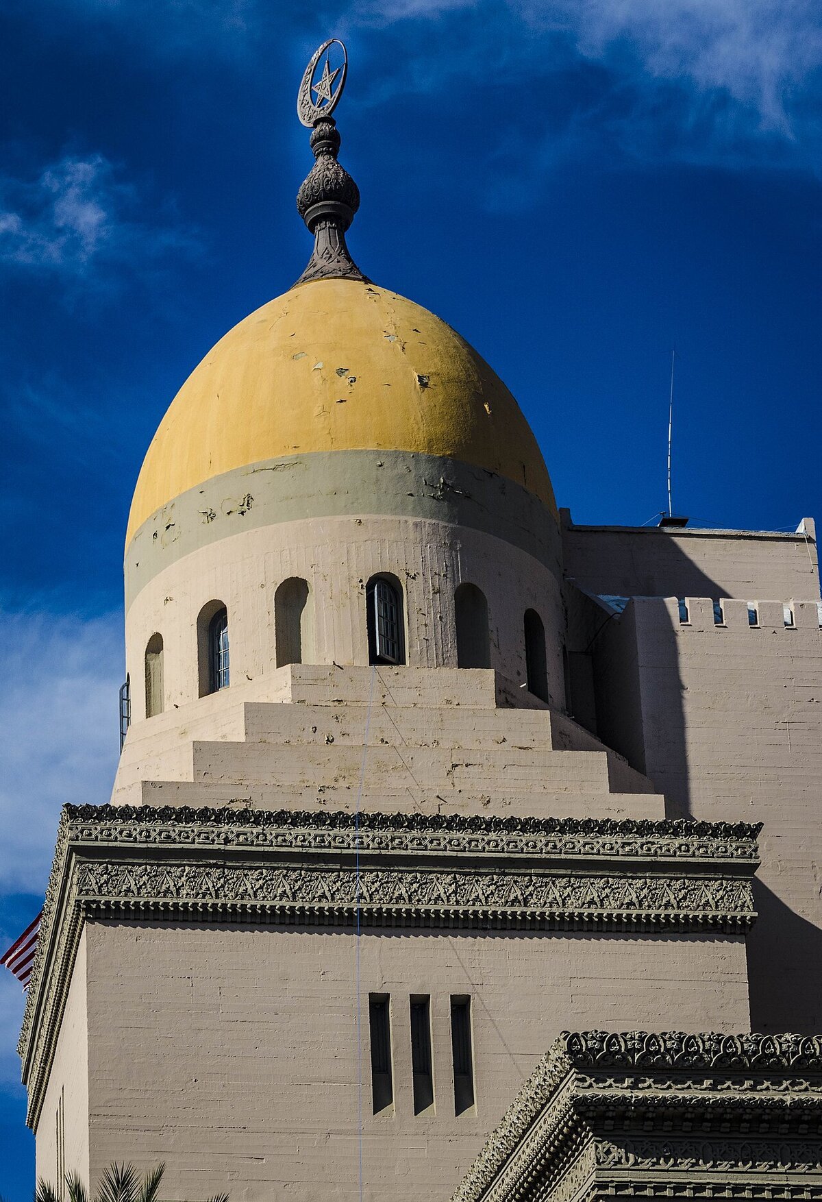 Yellow onion dome and carved stone trim of the Shrine Auditorium against a deep blue sky